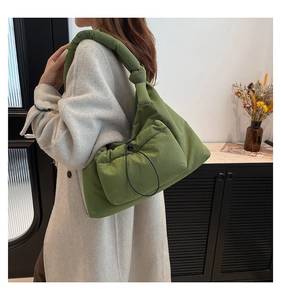 Detail of green quilted puffer shoulder bag featuring knotted strap and drawstring pocket