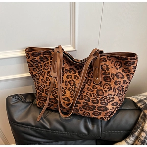 Detail view of large leopard print tote bag on a black leather sofa in a stylish setting