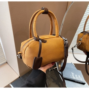 Detail of ginger suede mini Boston bag with dark brown leather handles and textured surface