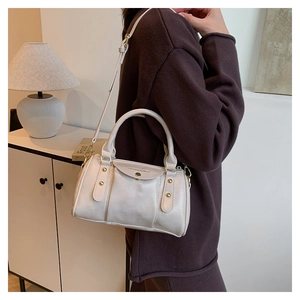 Detail of light beige crossbody bag with gold round clasp and delicate metal studs