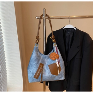 Detail of vintage canvas tote with leather straps and teddy pendant on a black blazer