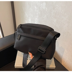 Detail of black nylon crossbody bag featuring multiple zippers and adjustable strap