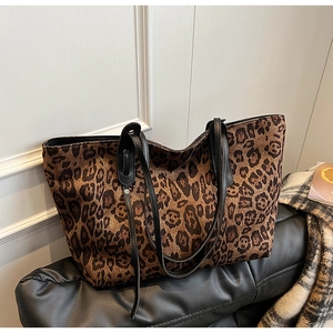 Detail of large leopard print tote bag with black straps on a leather sofa in a modern room