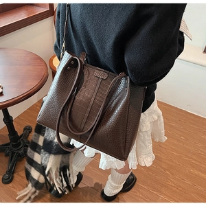 Detail of a dark brown crocodile embossed leather tote bag with elegant shoulder straps