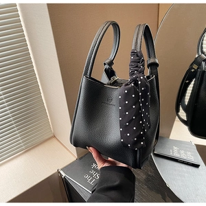 Detail of black lychee leather bucket bag with polka dot scarf and embossed logo