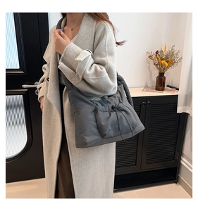 Detail of dark grey quilted nylon crossbody bag featuring functional drawstring front pocket