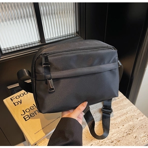 Close-up of lightweight black nylon crossbody bag with functional zipper compartments