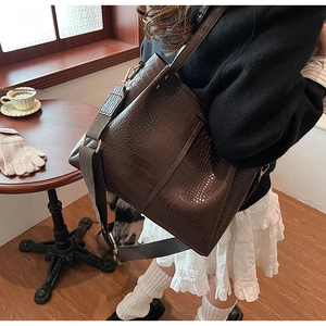 Detail view of dark coffee crocodile embossed tote bag with wide strap and gold hardware
