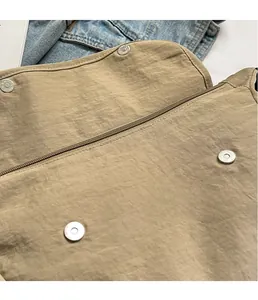Detail of khaki nylon bag showing four silver magnetic buckles and smooth zipper closure