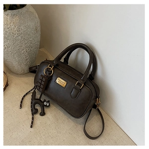 Detail view of brown vintage Boston bag with cute cat and chocolate bar charms