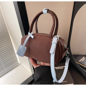Detail of Boston-style suede shoulder bag featuring brown body and blue strap accents