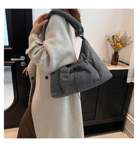 Detail of grey quilted nylon shoulder bag with drawstring pocket and knotted strap