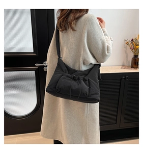 Detail of a large black padded tote bag with drawstring pocket and puffy shoulder strap