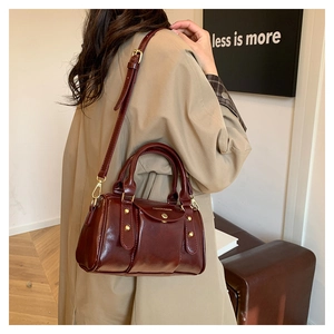 Detail of dark brown polished leather Boston bag with gold rivets and handle strap