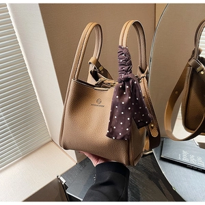 Brown lychee leather bucket bag with top handles and decorative polka dot silk scarf detail