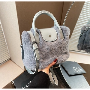 Détail d'un sac en fausse fourrure grise avec bandoulière en cuir bleu clair et boucles