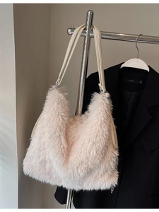 Fluffy cream faux fur tote bag with slim PU leather straps on a dark coat background
