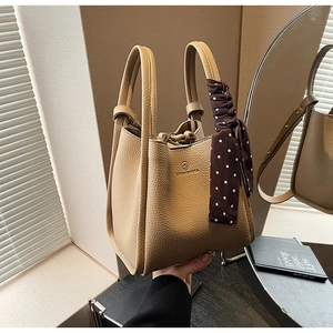 Close-up of khaki pebbled leather bucket bag with elegant polka dot silk scarf handle
