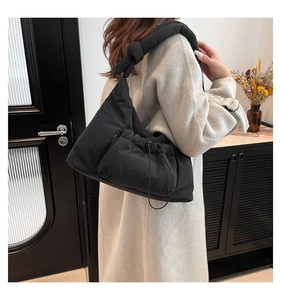 Detailed view of black quilted puffer tote bag with knotted strap and drawstring closure