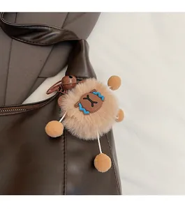 Dettaglio di un portachiavi a forma di orsetto marrone con campanello su borsa in pelle