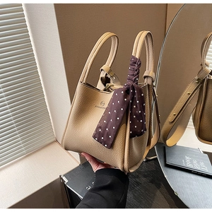 Close-up of beige lychee grain bucket bag with silk scarf detail on handle