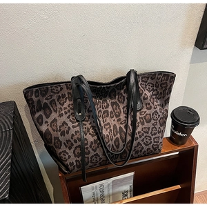 Detailed view of leopard print tote bag with black leather straps and large capacity