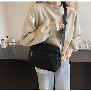 Close-up of black nylon crossbody bag with adjustable strap in casual lifestyle setting