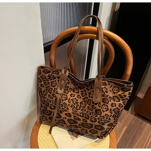 Detail view of leopard print tote bag placed on a vintage wooden chair against a white wall
