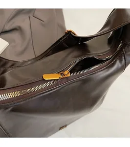 Vista macro dettagliata della chiusura a zip dorata sulla borsa tote in pelle marrone