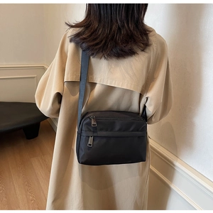 Rear view of a minimalist black waterproof nylon crossbody bag with adjustable strap