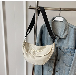 Detail of off-white crescent canvas bag with mountain line embroidery and black strap
