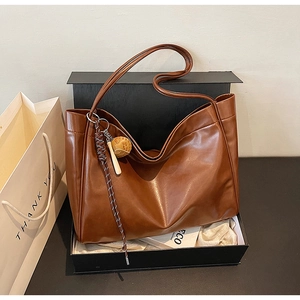 Detail of dark brown leather tote bag with baseball charm in black gift box