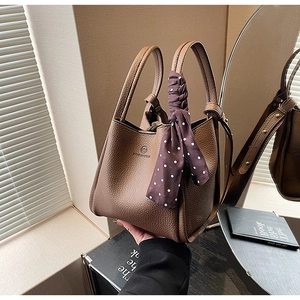 Detail of brown litchi pattern leather bucket bag with silk scarf and gold brand logo