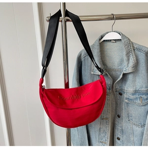 Detail of red canvas crescent bag with adjustable wide strap and embroidered mountain logo