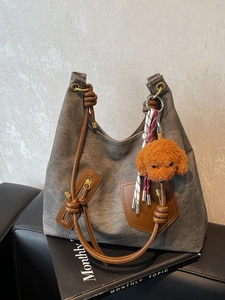 Retro canvas tote bag with leather trim and plush puppy charm on a black sofa