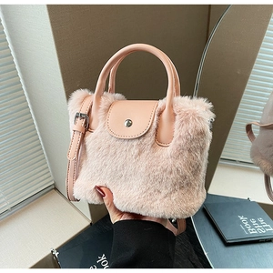 Détail du sac à main en peluche rose avec poignée en cuir et bandoulière réglable