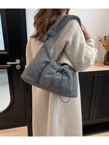 Minimalist grey quilted nylon shoulder bag for women shown in a modern interior setting