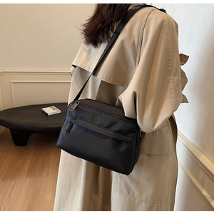 Detailed side view of a minimalist black waterproof nylon crossbody bag with wide strap
