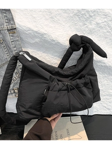 Minimalist black quilted nylon shoulder bag with knot strap and drawstring pocket detail