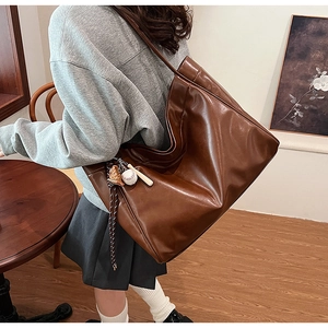 Detail of dark brown vintage tote bag featuring a sporty baseball keychain accessory