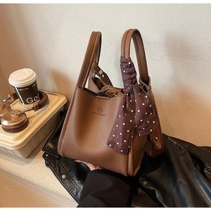 Detail of a brown lychee pattern bucket bag with an elegant decorative polka dot scarf