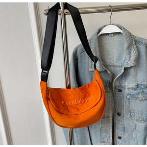 Detail of orange nylon moon bag with adjustable black strap and mountain line embroidery