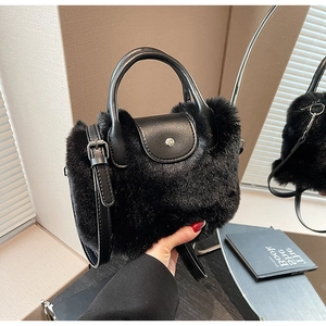 Détail du sac à main en peluche noire avec poignée en cuir et bouton pression métallique