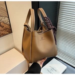 Detail of camel brown leather bucket bag with logo embossing and polka dot scarf detail