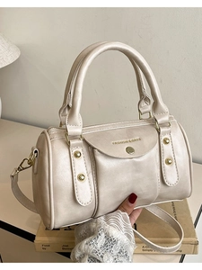 Creamy white cylindrical Boston handbag with dual handles and gold-tone hardware strap