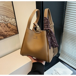Detailed close-up of brown pebbled leather bucket bag with elegant polka dot scarf accessory