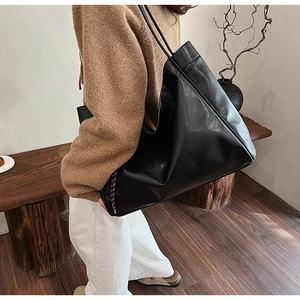 Detail of a large black leather tote bag with a soft slouchy silhouette and slim straps