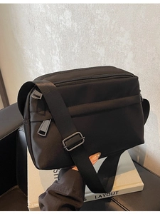 Minimalist black nylon crossbody bag with adjustable strap and metallic zipper detail