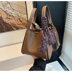 Detail of brown lychee leather bucket bag with handle scarf and embossed logo