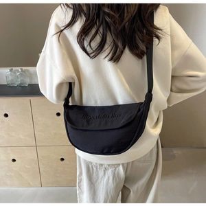 Close-up of black canvas crescent bag with mountain line logo and adjustable strap